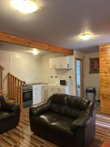 a living room with a leather couch and a kitchen at cabañas los Ulmos in Licán Ray