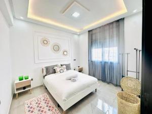 Una habitación blanca con una cama y una ventana en Elegant 3BR Stay 5min to Hay Riad, en Temara