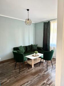 ein Wohnzimmer mit einer grünen Couch und einem Tisch in der Unterkunft Vasi City Stay in Weliko Tarnowo
