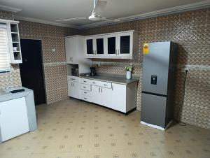 a kitchen with white cabinets and a refrigerator at Manresa House in Accra