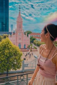 a woman standing on a balcony looking at a church at MOONLIGHT Hotel & Suites - The Best City View, Dragon Bridge view in Da Nang