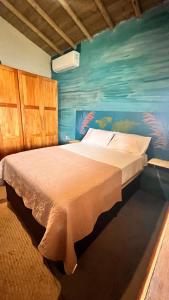a bedroom with a bed with a painting on the wall at Casa Beira rio Caraíva in Porto Seguro