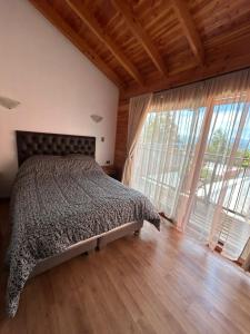a bedroom with a bed and a large window at cabañas los Ulmos in Licán Ray