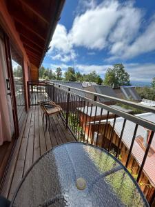 a balcony with a glass table and chairs on it at cabañas los Ulmos in Licán Ray
