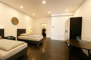 une chambre avec deux lits, une table et un bureau dans l'établissement Werre Apartments mit Smart-TV - stilvol, zentral & wohnlich, à Löhne