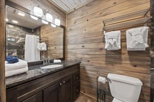 a bathroom with a toilet and a sink and a mirror at Rustic Retreat — Easy Access, Peaceful Setting, Close to Everything in Sevierville +35 photos