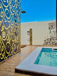 a swimming pool in a gym with a painting on the wall at Villa Sabrina in Awlād ‘Umar