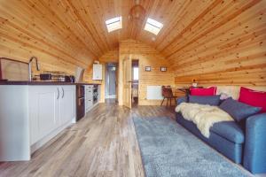 een woonkamer met een blauwe bank en een keuken bij Winter Recharge - Secluded Luxury Cabins with stream, stargazing, bookable sauna, walks and nature - Fell Farm Hideaway in Colwell +73 foto's