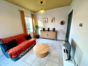 Gîte avec Terrasse et parking privé في Charnècles: غرفة معيشة مع أريكة حمراء وطاولة +18 صورة