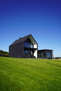 a black house on a field with a green field at Black barn in Rusinowo