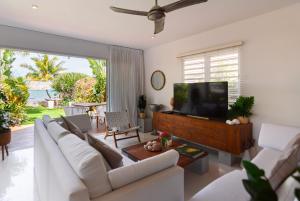 Villa MAEVA is your perfect beachfront escape في Roches Noires: غرفة معيشة مع أريكة بيضاء وتلفزيون بشاشة مسطحة