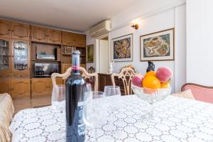 a bottle of wine sitting on a table with a bowl of fruit at Vemar Apartment - Near the beach, Private parking in Dubrovnik +23 photos