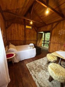 a bedroom with a bed in a wooden room at Pousada Quintal Verde in Guabiruba