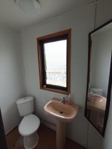 ein Badezimmer mit Toilette und Waschbecken und einem Fenster in der Unterkunft Mate Sur Hostal in Cochrane + 19 Fotos