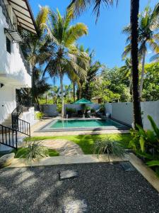een achtertuin met een zwembad en palmbomen bij Kingsman Villa in Mirissa