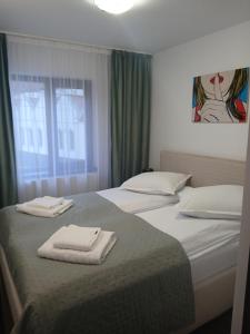 una camera da letto con due letti con asciugamani sopra di Mini Apartament a Buşteni
