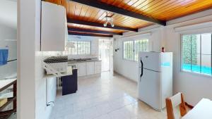 een keuken met witte apparatuur en een houten plafond bij Casa Tipo Loft- Tigre Centro Con Jardin, Parrilla Y Pileta de Lona Grande 4 Personas in Tigre