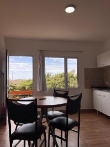 een eetkamer met een tafel en stoelen en een raam bij Brusa in Las Grutas