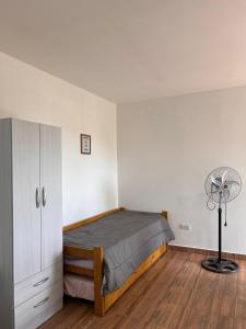 een slaapkamer met een bed, een bureau en een ventilator bij Brusa in Las Grutas