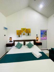 een slaapkamer met een groot wit bed met blauwe kussens bij Kingsman Villa in Mirissa +105 foto's