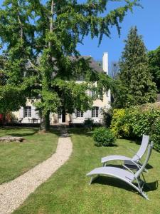 a white bench sitting in the grass in front of a house at Manoir la Meffrais 1741-Chambres d'hôtes à 3 min de Dinan-Parking Privé in Dinan