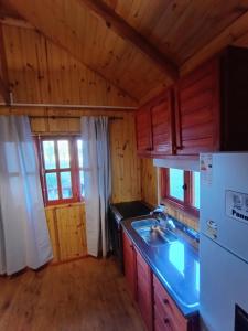 Una cocina con gabinetes de madera y un refrigerador blanco. en Kiya surf cabaña, en Colonia Chapadmalal 3 fotos más