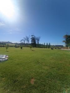 Un gran campo de hierba con árboles en la distancia. en Kiya surf cabaña, en Colonia Chapadmalal