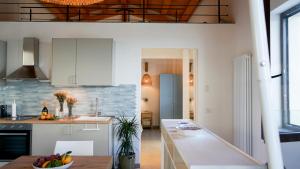 a kitchen with white cabinets and a table with a bowl of fruit at Palazzo Cettina Sul Mare in Cefalù