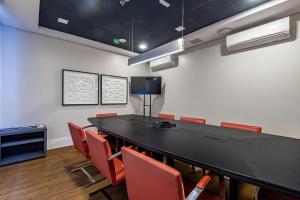 Helbor Stay Santos في سانتوس: قاعة اجتماعات مع طاولة سوداء وكراسي حمراء +291 صورة