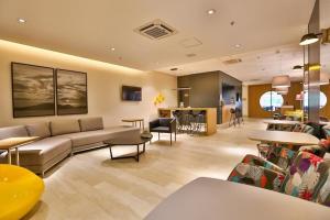 Helbor Stay Santos في سانتوس: غرفة معيشة كبيرة مع أريكة وطاولات