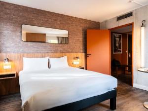 ein Schlafzimmer mit einem großen weißen Bett und einem Spiegel in der Unterkunft Ibis Styles Lyon Villeurbanne Parc de la Tête d'Or in Villeurbanne