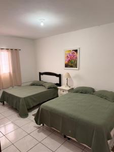 a bedroom with two beds and a table with a lamp at Taba House in São Gabriel