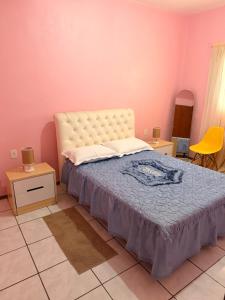 a bedroom with a bed and two tables and a yellow chair at Taba House in São Gabriel