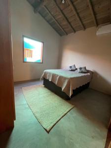 a bedroom with a bed with a rug and a window at Casa Beira rio Caraíva in Porto Seguro