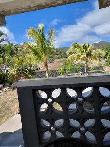 a balcony with a view of the beach and palm trees at Ecofriendly Apartment in Gated Residence in Saint Martin