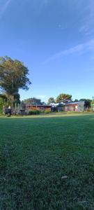 un campo de césped verde con casas en el fondo en Kiya surf hostel, en Colonia Chapadmalal