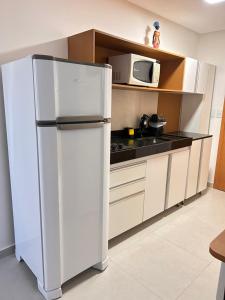 a kitchen with a white refrigerator and a microwave at Villas do Porto Residence by La Playa in Porto De Galinhas