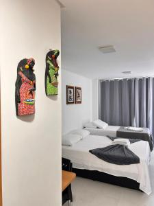two beds in a room with two masks on the wall at Villas do Porto Residence by La Playa in Porto De Galinhas