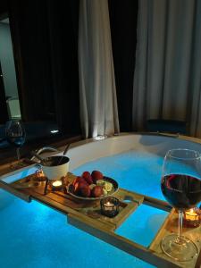 a hot tub with a plate of food and a glass of wine at Reserva Mauá chalés in Visconde De Maua