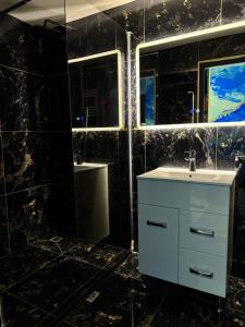 ein Badezimmer mit einem weißen Waschbecken und einem Spiegel in der Unterkunft Casa Daiana in Aninoasa