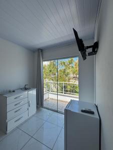 a white kitchen with a large window and a refrigerator at Residencial Dona Duda in Bombinhas