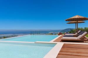 een zwembad met ligstoelen en een parasol bij Anemones Villas by Omikron Selections in Spanokhórion +69 foto's