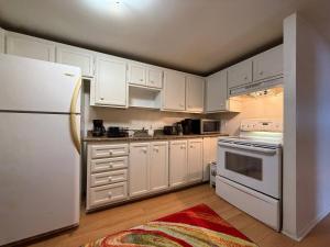 eine Küche mit weißen Schränken und einem weißen Kühlschrank in der Unterkunft Free Parking! Fast Wifi! Comfortable 3BR Apt for Montreal Explorers & Adventure! in Montreal