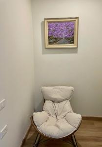 Ein weißer Stuhl in einer Ecke, an der Wand ein Gemälde. in der Unterkunft Căn hộ sapa in Sa Pa