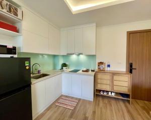 eine Küche mit weißen Schränken und einem schwarzen Kühlschrank in der Unterkunft Căn hộ sapa in Sa Pa