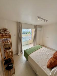 イリェウスにあるApê a 100m do mar com piscina no condomínioのベッドと大きな窓のある寝室