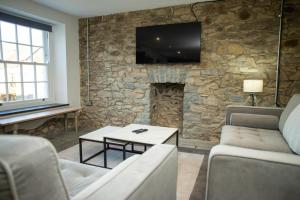 een woonkamer met een stenen muur en een tv bij Gelli Genlas Aberaeron in Synod