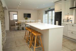 een keuken met een wit aanrecht en houten krukken bij Gelli Genlas Aberaeron in Synod