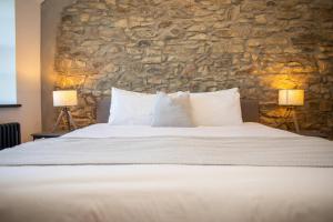 een slaapkamer met een groot bed en een stenen muur bij Gelli Genlas Aberaeron in Synod