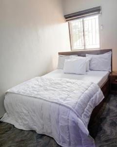 a bedroom with a large bed with white sheets and a window at J-D Suites in Ozuoba